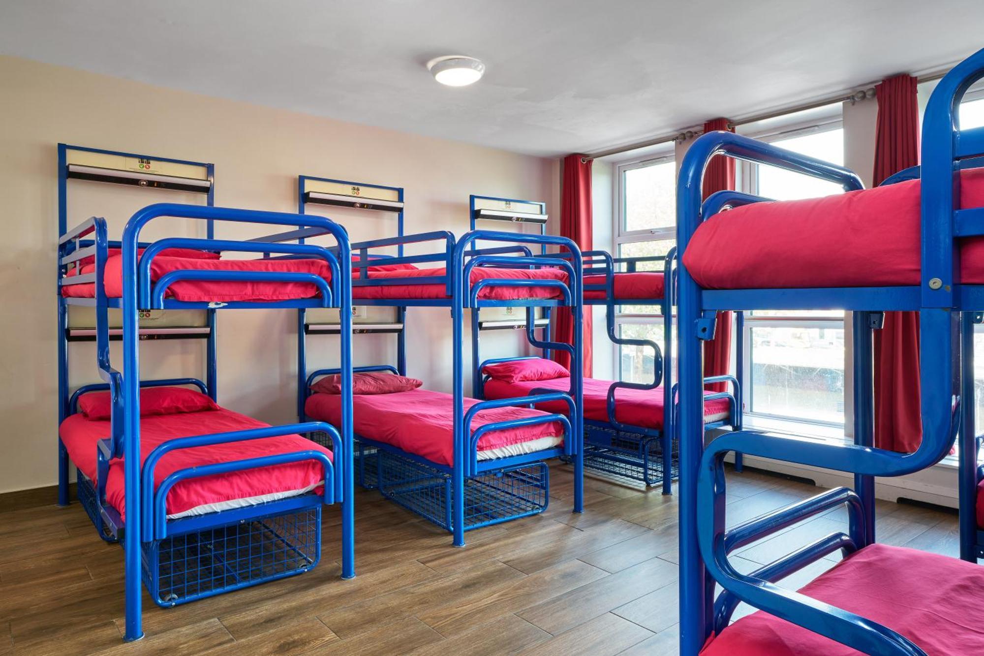 Cama en habitación compartida femenina con 10 camas y baño